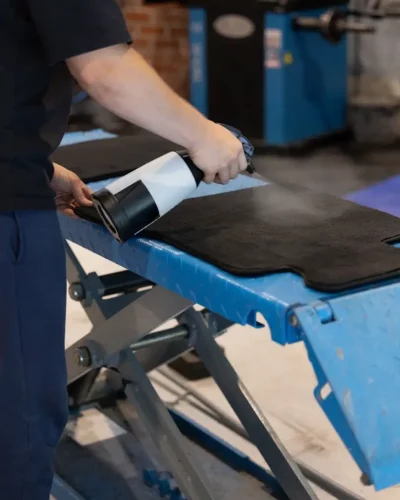 Behandlung einer Fußmatte mit einem Sprühgerät in der Werkstatt.
